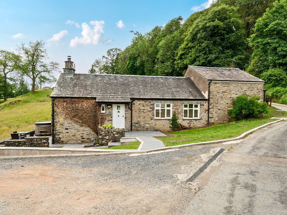 A stone house with a pathway and trees at Dove Cottage at the Graythwaite Estate near Hawkshead