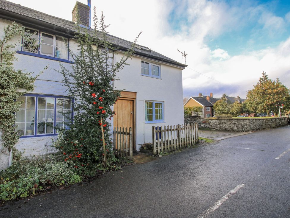 A house with a fence and bush at Marigold Cottage in Clun near Bishop's Castle