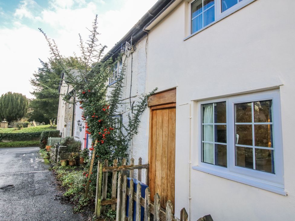A view of a house with a wooden door and window at Marigold Cottage in Clun near Bishop's Castle