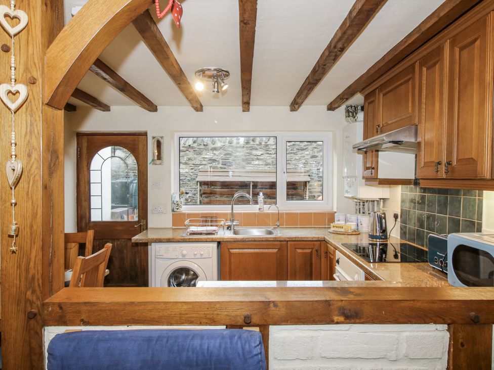 A kitchen with wooden cabinets and appliances at Marigold Cottage Clun near Bishop's Castle