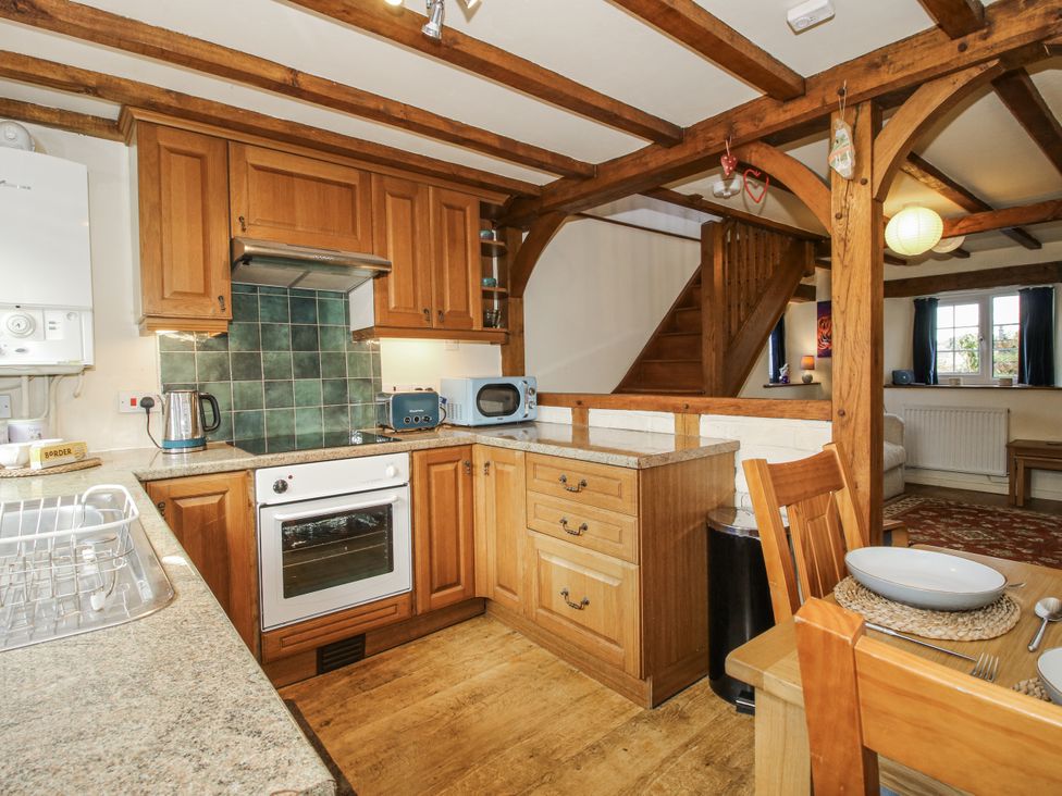 A kitchen with wooden cabinets and an oven at Marigold Cottage in Clun near Bishop's Castle