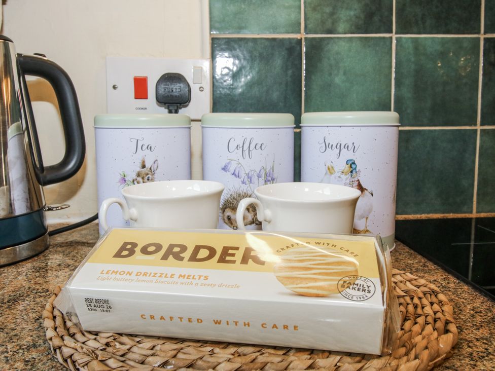 A kitchen with a kettle, canisters and cookies at Marigold Cottage Clun near Bishop's Castle