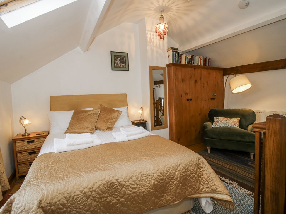 A bedroom with a bed and wardrobe at Marigold Cottage in Clun near Bishop's Castle