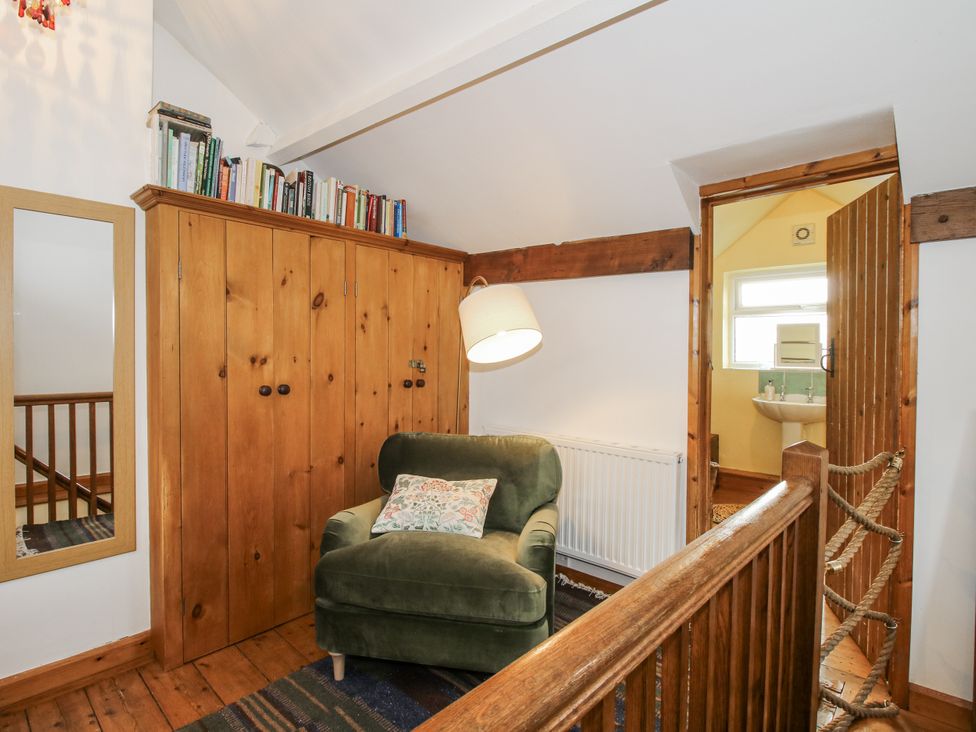 A landing with a chair and bookshelf at Marigold Cottage in Clun near Bishop's Castle