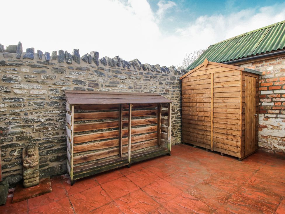 A garden with wooden storage unit and shed at Marigold Cottage in Clun near Bishop's Castle