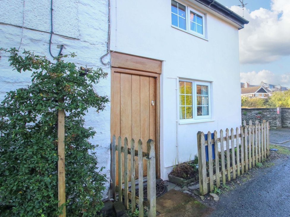 An exterior view of a cottage with a wooden door and fence at Marigold Cottage in Clun near Bishop's Castle