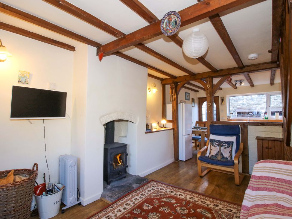 A living room with a wood stove and wooden furniture at Marigold Cottage in Clun near Bishop's Castle