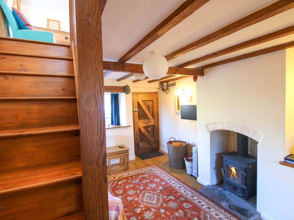 A living room with a fireplace and staircase at Marigold Cottage, Clun near Bishop's Castle