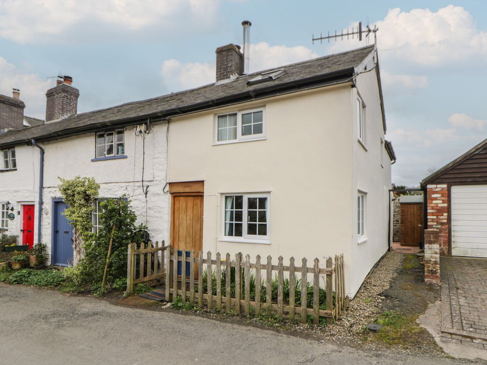 A house with a wooden door and windows in an outdoor area at Marigold Cottage in Clun near Bishop's Castle