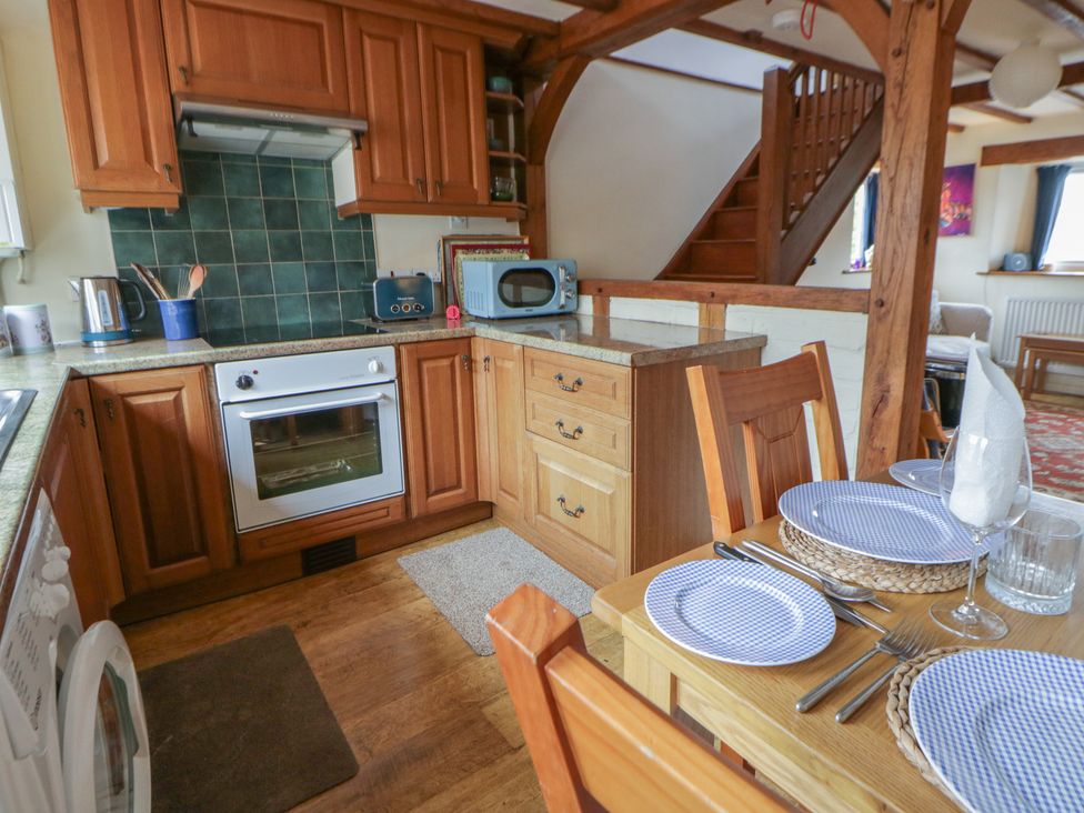 A kitchen with wooden cabinets and dining table at Marigold Cottage in Clun near Bishop's Castle