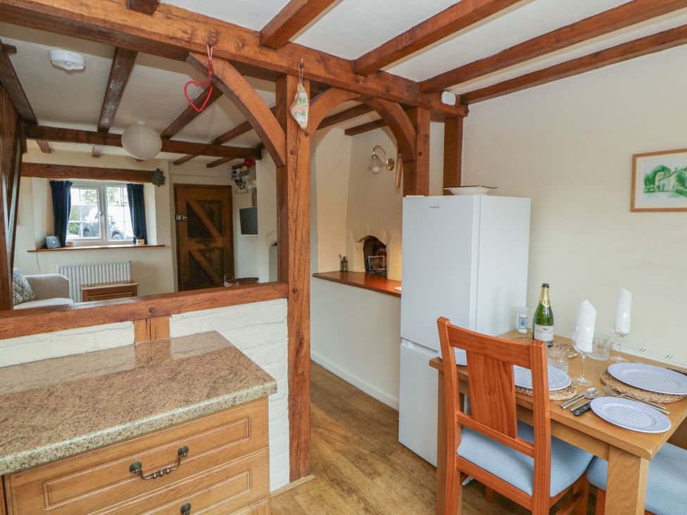 A kitchen with dining table and refrigerator at Marigold Cottage in Clun near Bishop's Castle