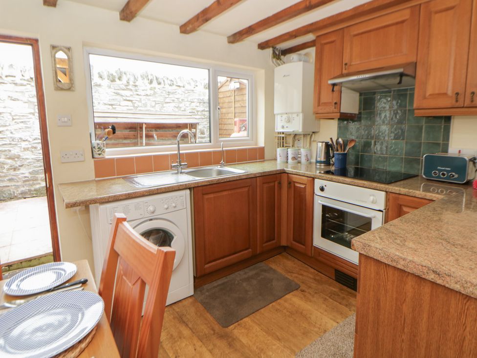 A kitchen with appliances and wooden cabinets at Marigold Cottage in Clun near Bishop's Castle