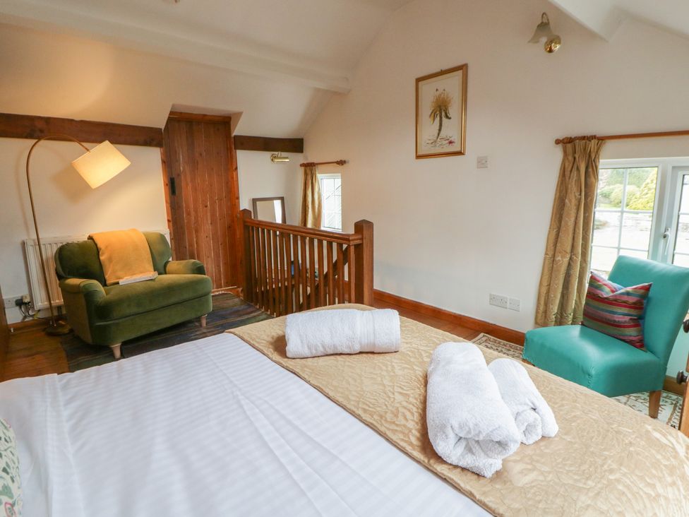A bedroom with a bed and armchair at Marigold Cottage in Clun near Bishop's Castle