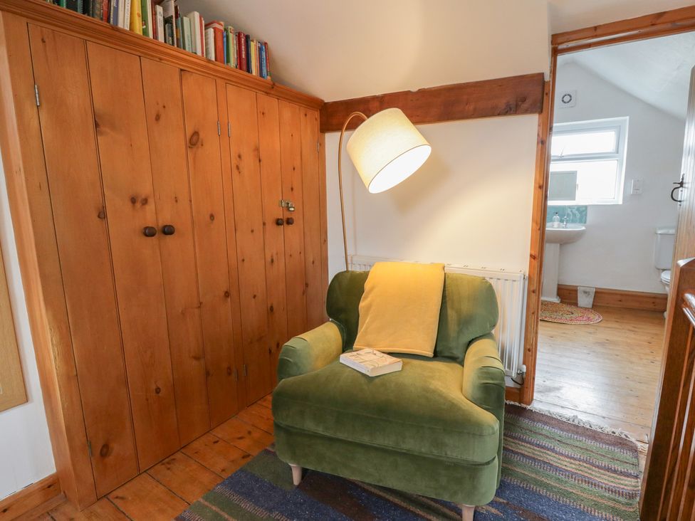 A snug with an armchair and bookshelf at Marigold Cottage in Clun near Bishop's Castle