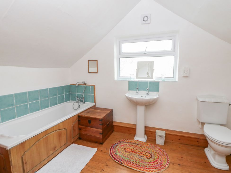 A bathroom with a bath tub, sink, and toilet at Marigold Cottage in Clun near Bishop's Castle