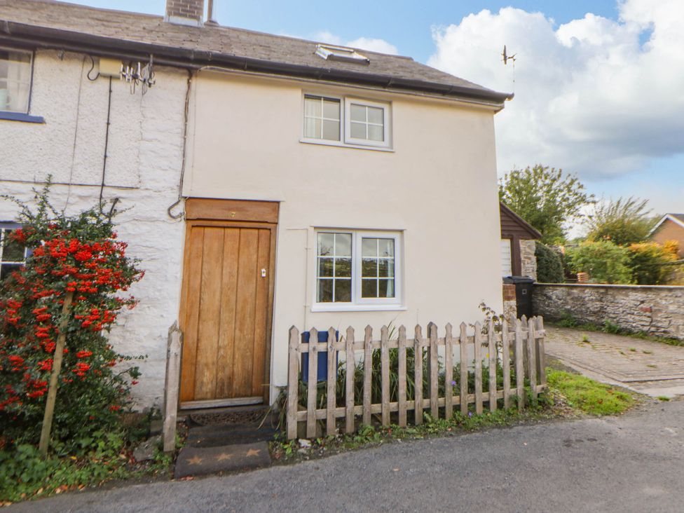 A house with a wooden door and fence at Marigold Cottage in Clun near Bishop's Castle