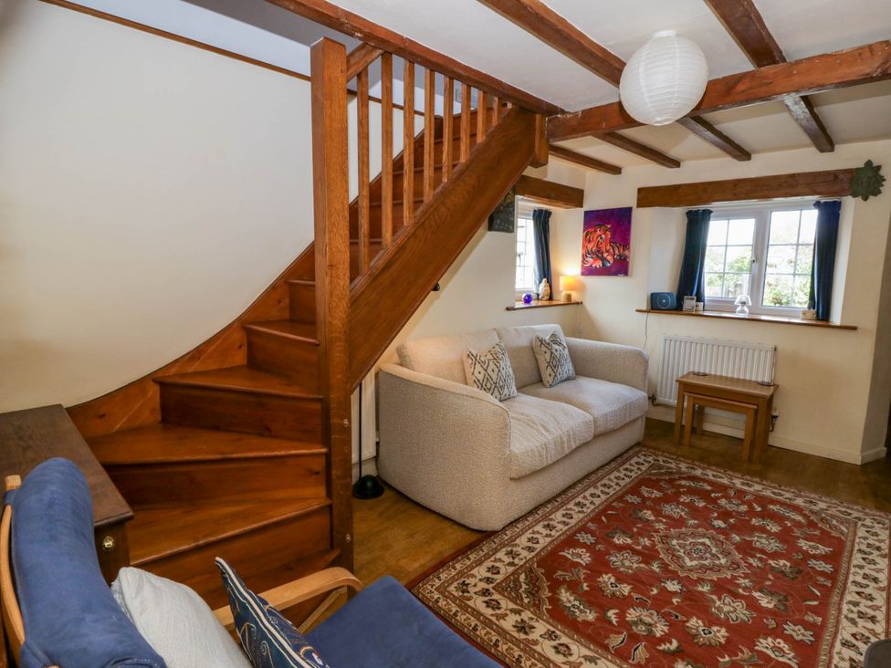 A living room with a staircase and sofa at Marigold Cottage in Clun near Bishop's Castle