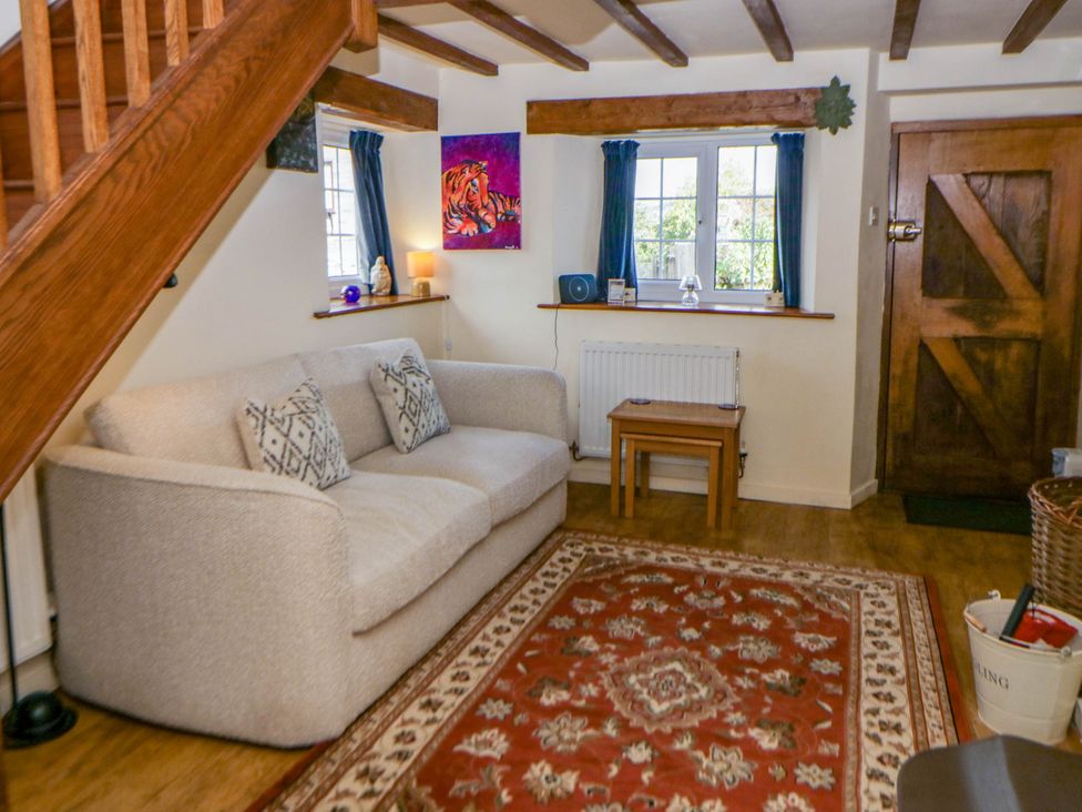 A living room featuring a sofa, table, and window at Marigold Cottage in Clun near Bishop's Castle