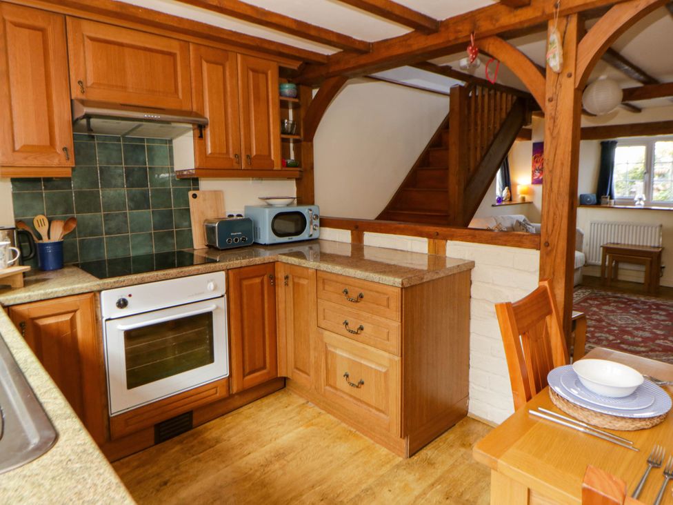 A kitchen with wooden cabinets and appliances at Marigold Cottage in Clun near Bishop's Castle