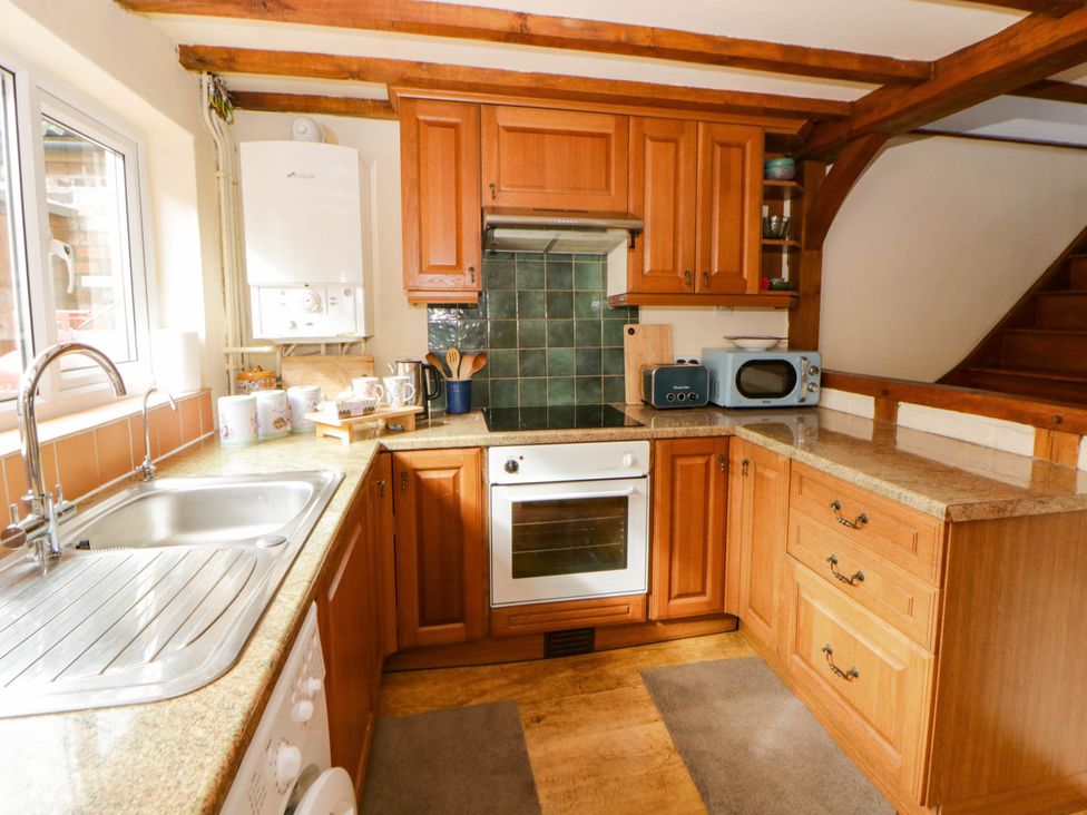 A kitchen with wooden cabinets and appliances at Marigold Cottage in Clun near Bishop's Castle