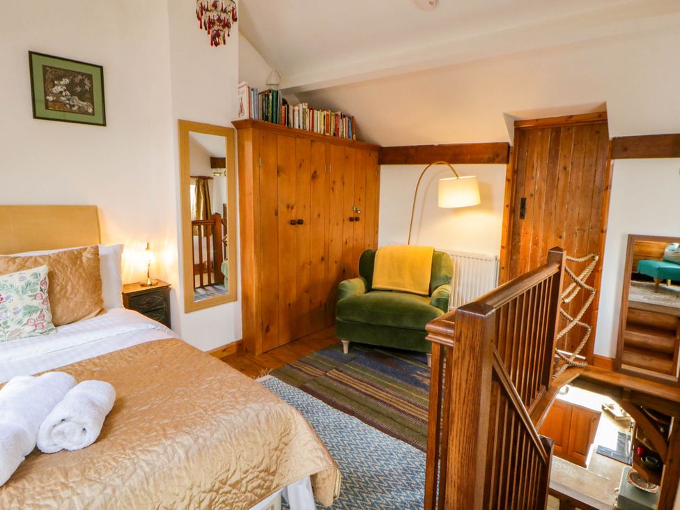 A bedroom with a bed and wardrobe at Marigold Cottage in Clun near Bishop's Castle