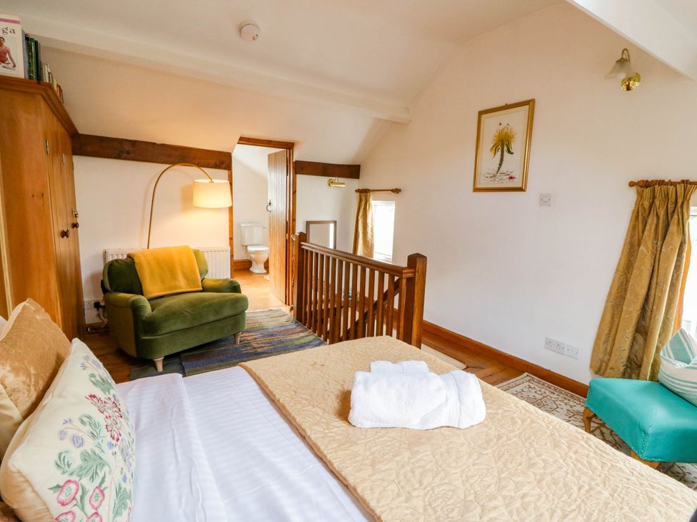 A bedroom with a bed and armchair at Marigold Cottage in Clun near Bishop's Castle