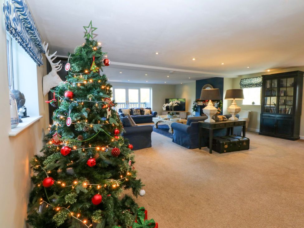 A living room with a Christmas tree and seating area at Nant-yr-Rhedyn in Red Wharf Bay
