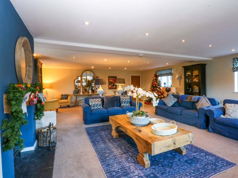 A living room with a Christmas tree and seating arrangements at Nant-yr-Rhedyn Red Wharf Bay