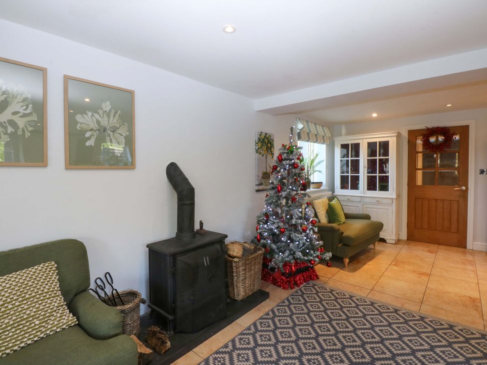 A living room with a Christmas tree and a wood stove at Nant-yr-Rhedyn in Red Wharf Bay