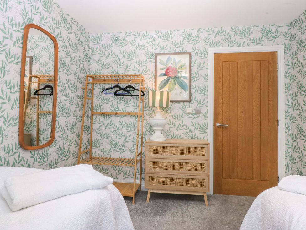 A bedroom with a clothes rack and a lamp at Nant-yr-Rhedyn in Red Wharf Bay