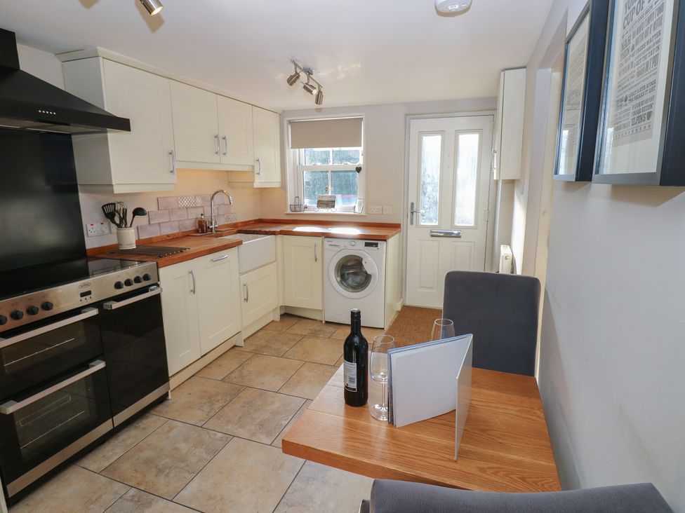 A kitchen with cabinets, washing machine and dining table at Hillside View in Hawes