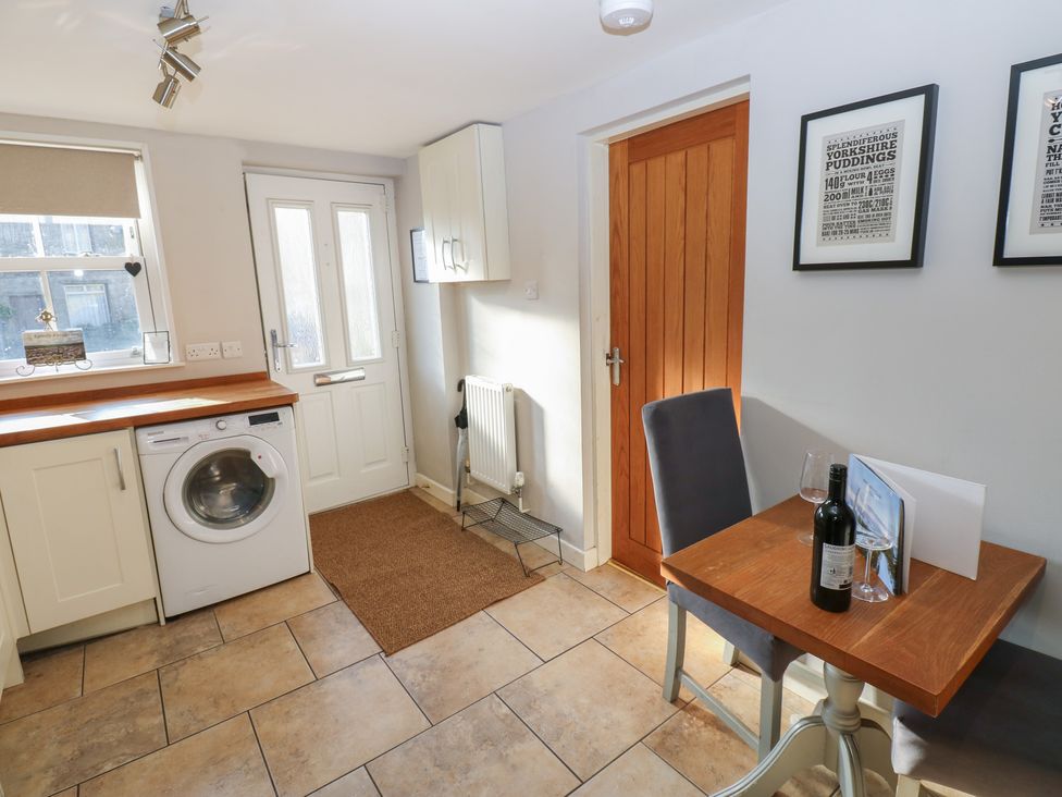 A kitchen with a washing machine and table at Hillside View in Hawes