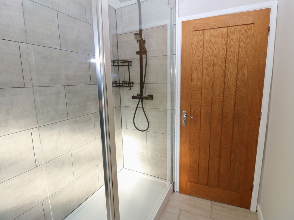 A shower area with glass door and wooden door at Hillside View in Hawes