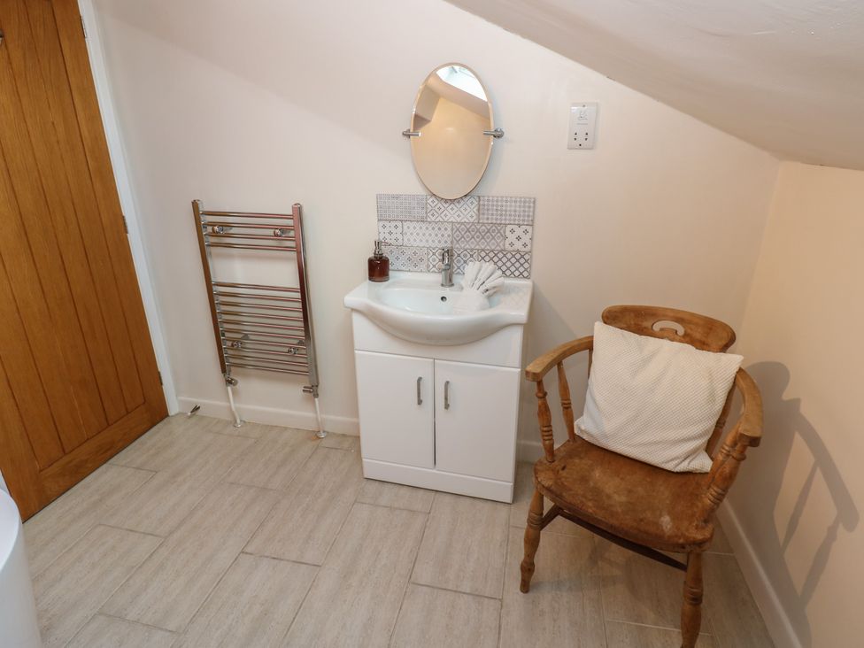 A bathroom featuring a sink, mirror, heated towel rail, and chair at Hillside View in Hawes