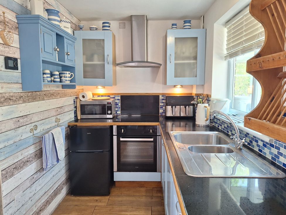 A kitchen with a fridge, sink, oven, and cabinets at Wood Glen Cottage in Rushlake Green near Heathfield
