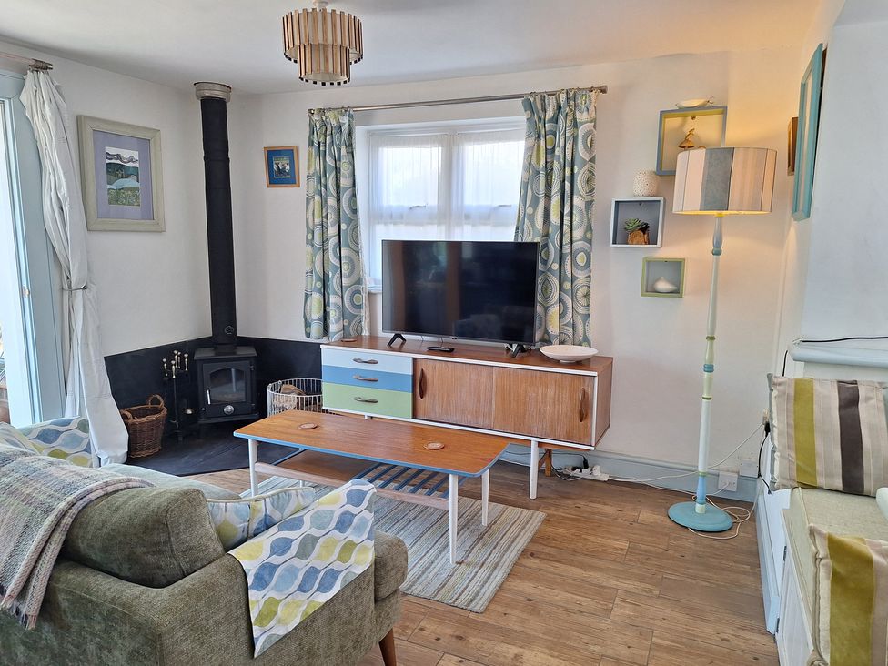 A living room with a sofa, coffee table, and television at Wood Glen Cottage, Rushlake Green near Heathfield