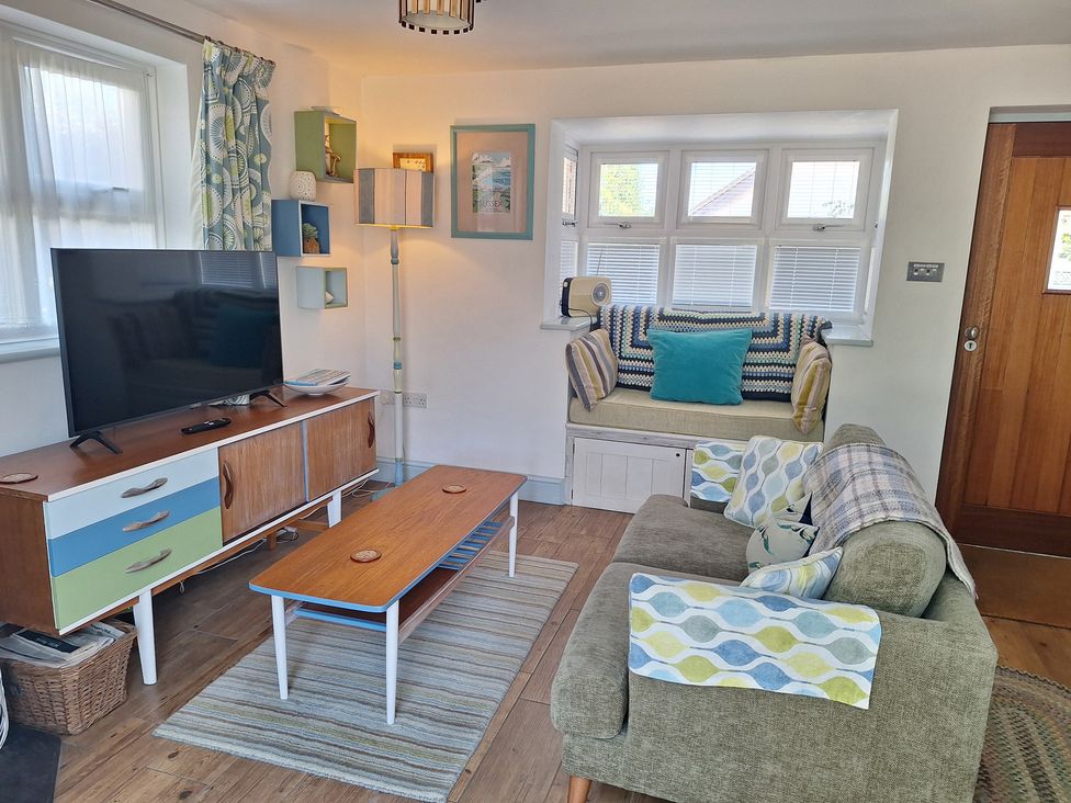 A living room with a television and sofa at Wood Glen Cottage in Rushlake Green near Heathfield