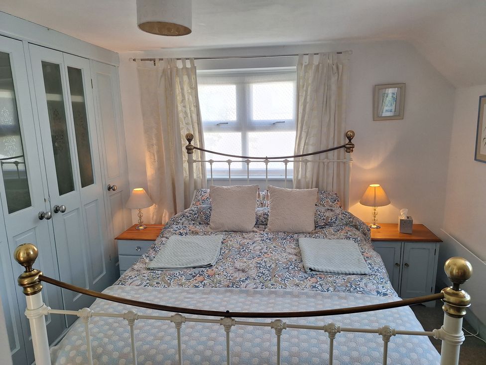 A bedroom with a bed, wardrobe, and lamp at Wood Glen Cottage in Rushlake Green near Heathfield