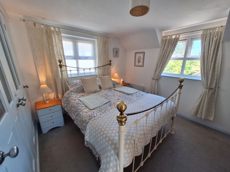 A bedroom with a bed and nightstand at Wood Glen Cottage in Rushlake Green near Heathfield