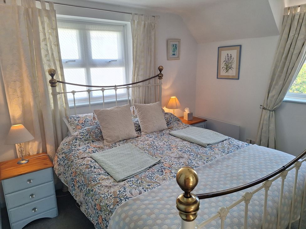 A bedroom with a bed and bedside table at Wood Glen Cottage in Rushlake Green near Heathfield