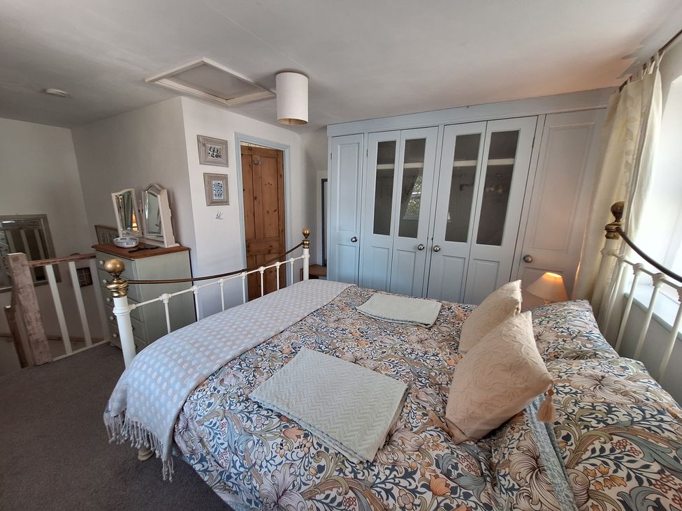 A bedroom with a bed and wardrobe at Wood Glen Cottage in Rushlake Green near Heathfield