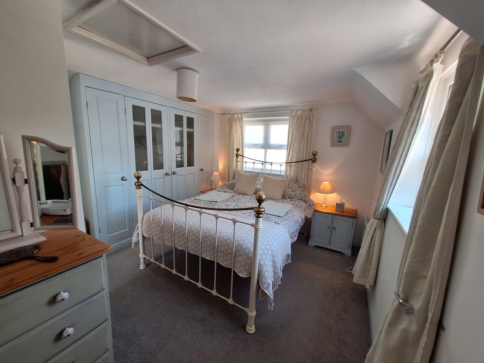 A bedroom with a bed and wardrobe at Wood Glen Cottage in Rushlake Green near Heathfield