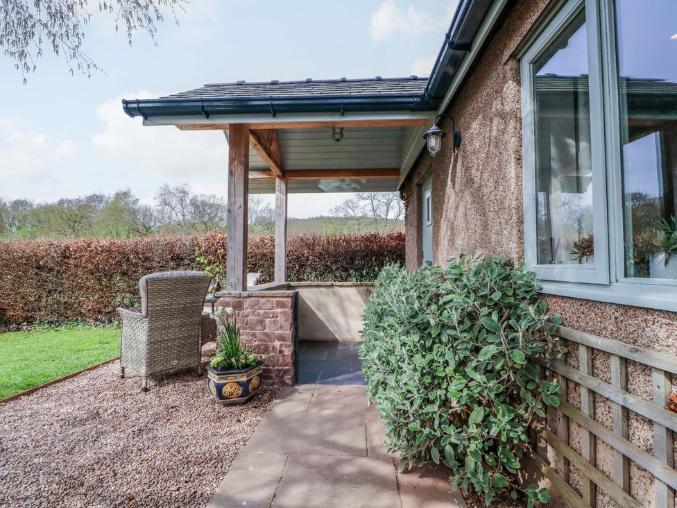 An outdoor porch with a chair and plants at The Lodge, Lower Trefedw near Abergavenny