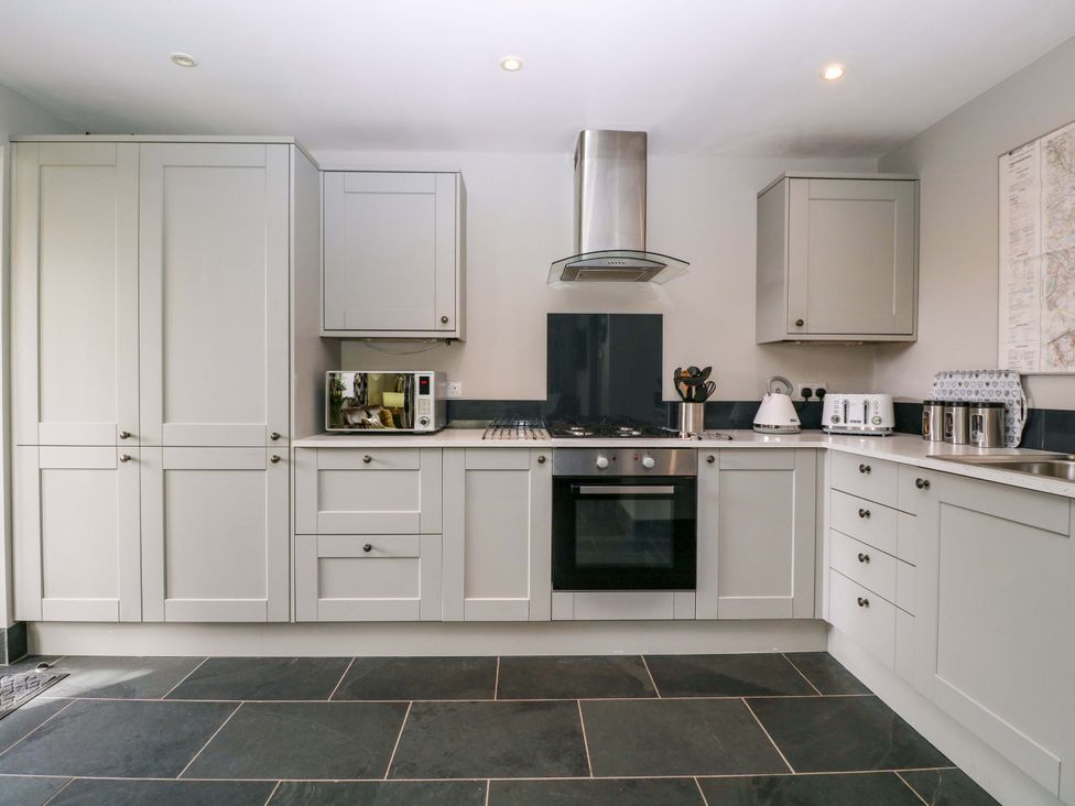 A kitchen with gray cabinets and appliances including a microwave and stove at The Lodge, Lower Trefedw Pandy near Abergavenny