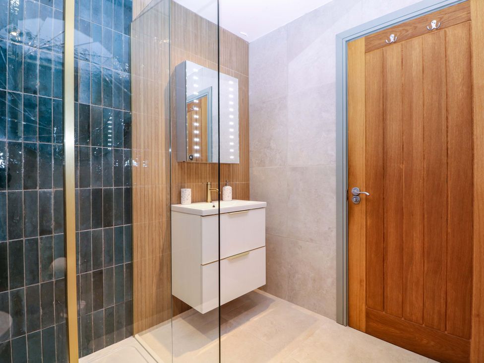 A bathroom with a shower, sink, and mirror at The Lodge, Lower Trefedw in Pandy near Abergavenny