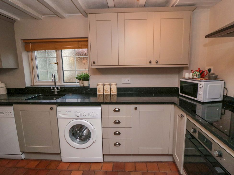 A kitchen with a washing machine and microwave at Jasmine Cottage in Dalton Near Thirsk