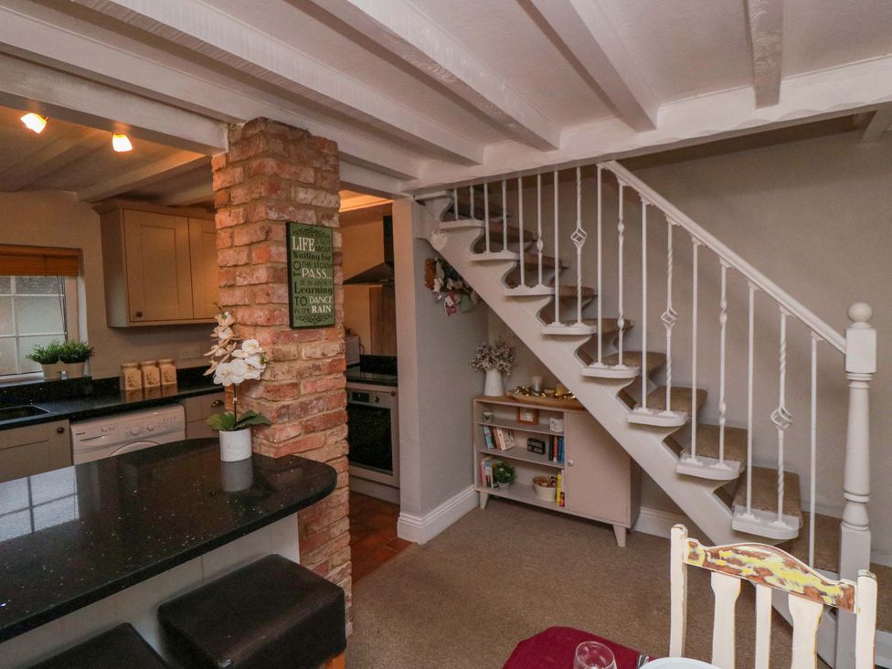 A kitchen with a staircase and wooden cabinets at Jasmine Cottage Dalton Near Thirsk