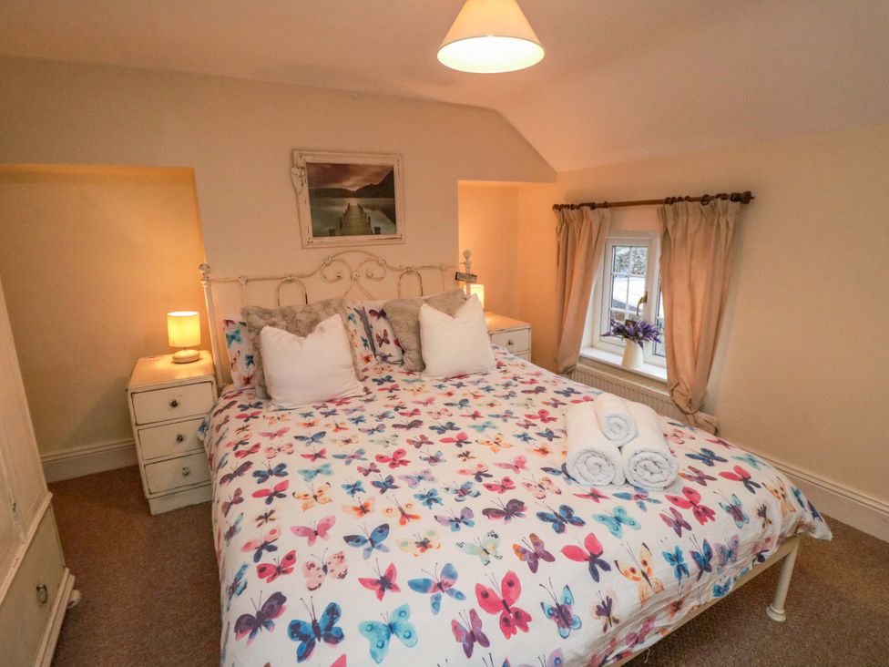 A bedroom with a bed and bedside table at Jasmine Cottage in Dalton Near Thirsk
