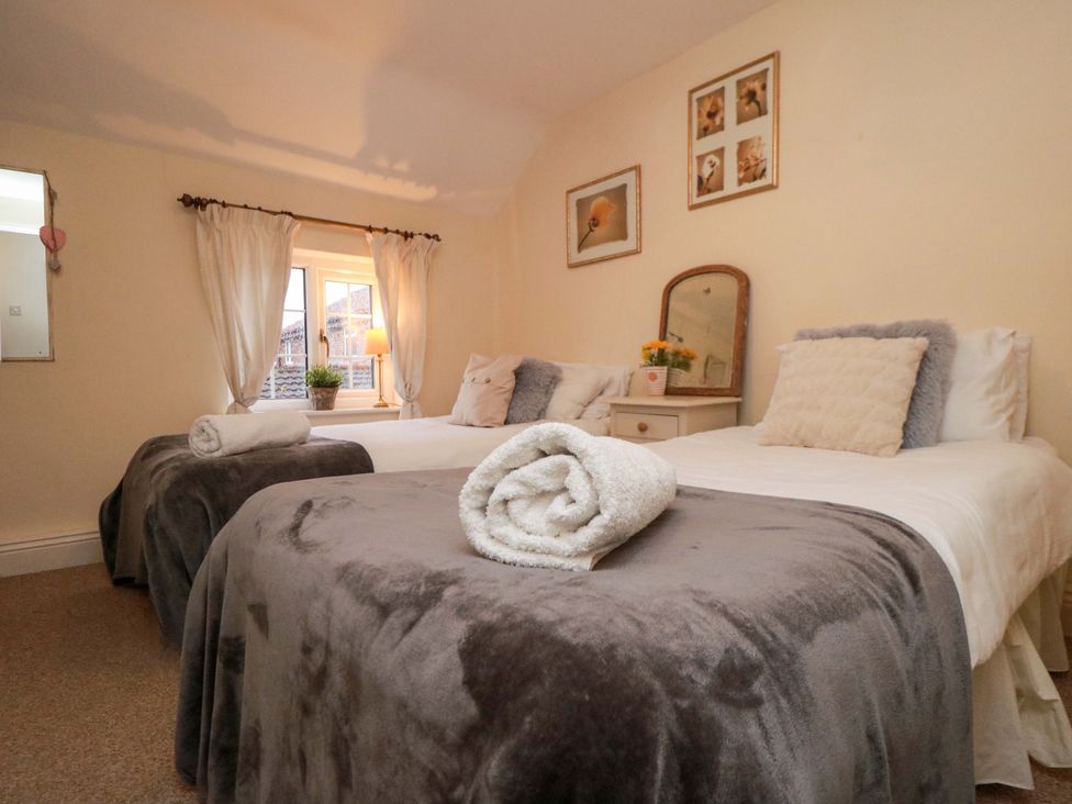 A bedroom with two beds and a bedside table at Jasmine Cottage Dalton Near Thirsk