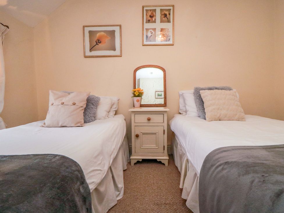 A bedroom with two beds and a mirror at Jasmine Cottage in Dalton Near Thirsk